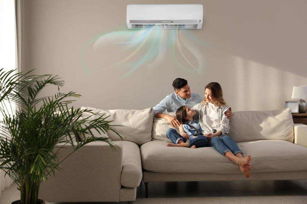 Happy family resting under air conditioner